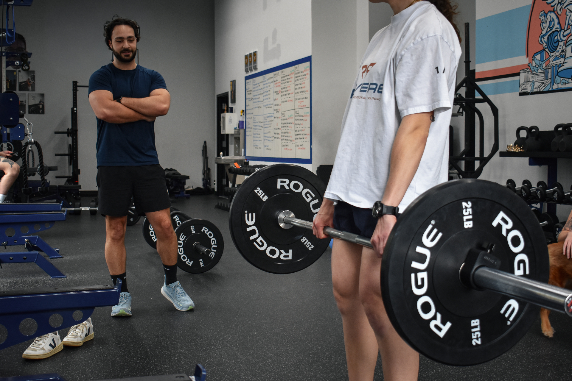 Coach guiding a client through a barbell squat
